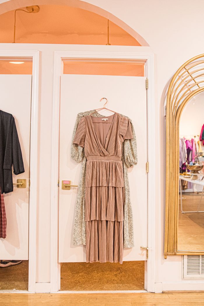 Elegant dress hanging in a Charlotte boutique fitting room, showcasing style and sophistication.