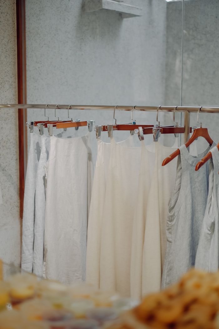 A selection of white and neutral colored dresses hanging on a rack in a boutique setting. Perfect for fashion and retail themes.