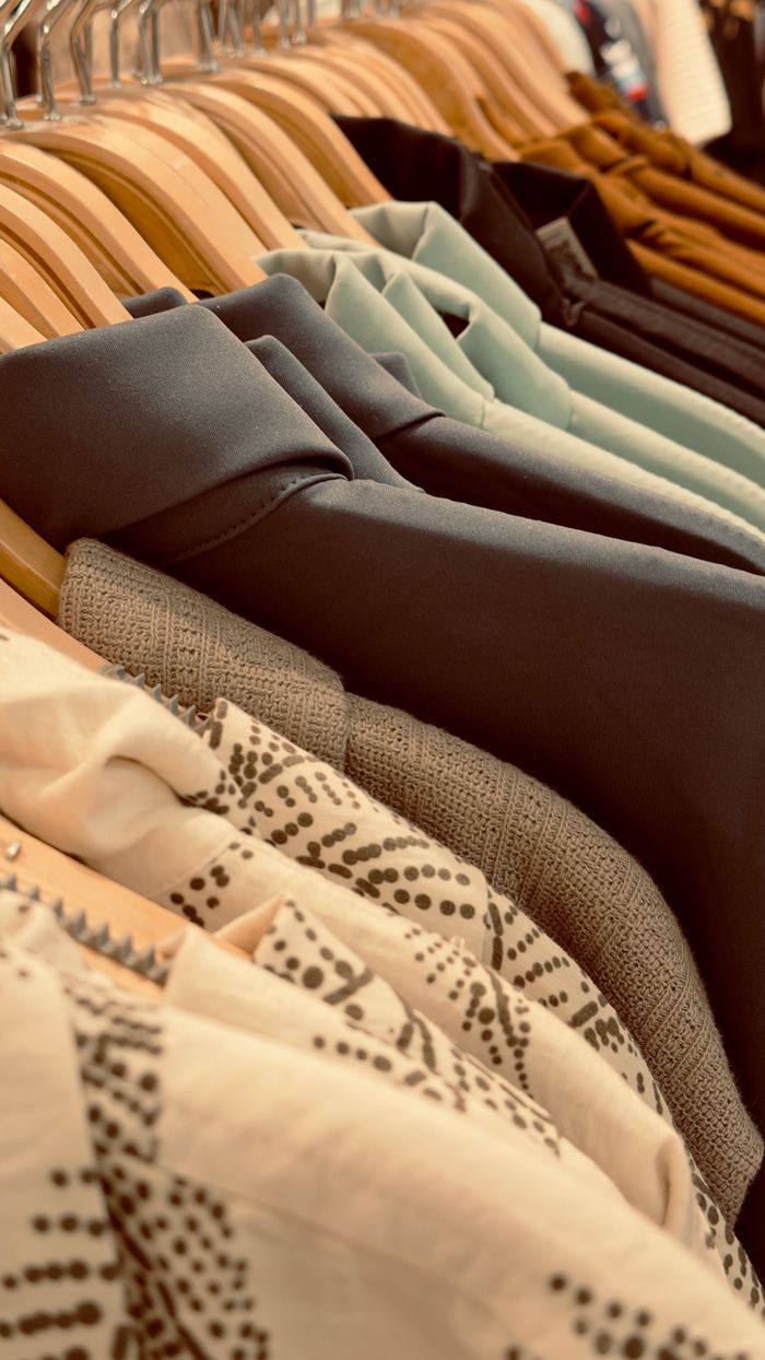 A vibrant variety of clothes displayed on wooden hangers, showcasing fashion and style.