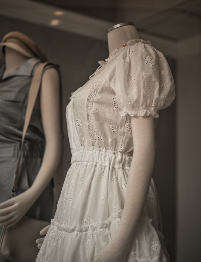 Chic white lace dress on mannequin highlighting intricate garment design in a fashion store.